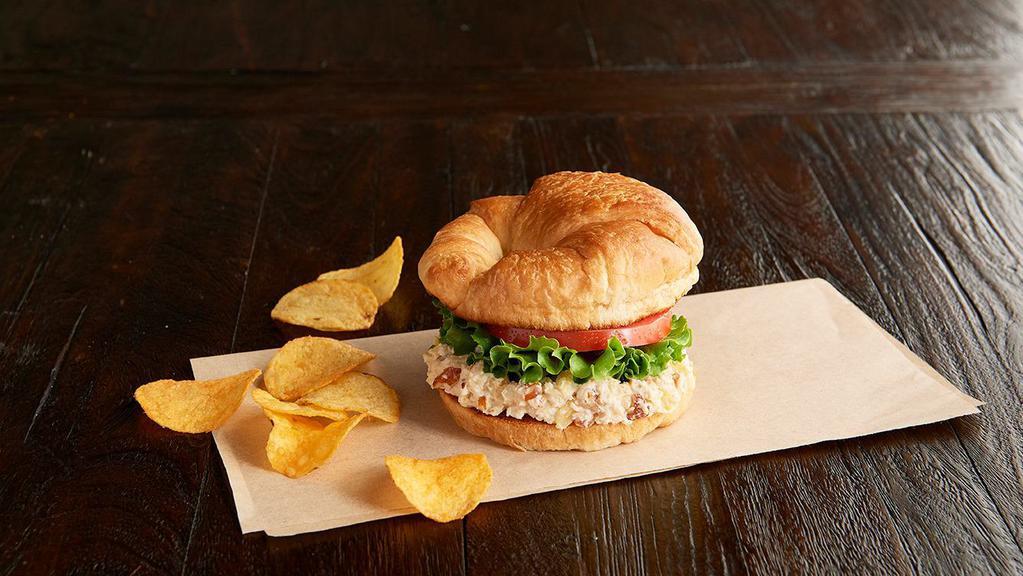 Shelley'S Deli Chick Regular · Our family-recipe chicken salad with almonds and pineapple, leafy lettuce, tomato, on a toasted croissant. Served with chips or baked chips (150/100 cal) and a pickle (5 cal).