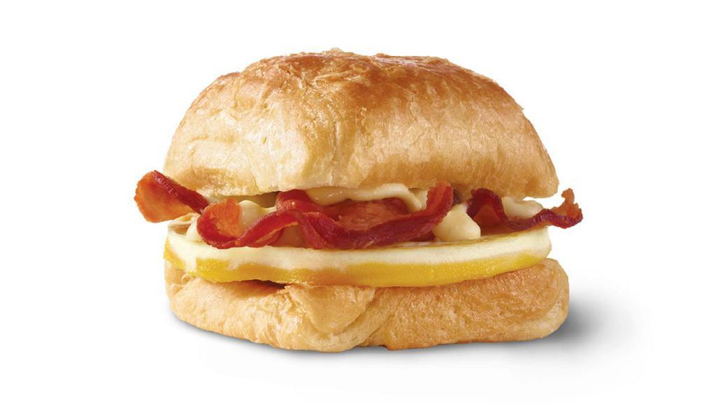 Bacon, Egg & Swiss Croissant · A fresh-cracked grade A egg and Applewood smoked bacon covered in creamy swiss cheese sauce on a flaky croissant bun. Breakfast basics worth waking up early for.