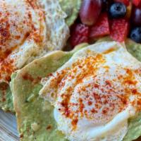 Avocado And Egg Toast · Fresh avocado spread generously on 2 pieces of toast topped with fried eggs, side of fruit