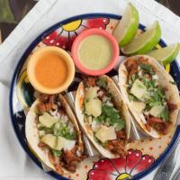 Tacos Al Pastor · Three tacos filled with marinated pork and fresh pineapple.