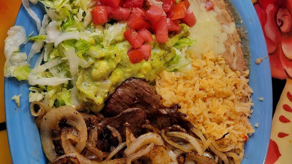 Carne Asada · Well-seasoned grilled skirt steak topped with grilled onions. Served with rice, beans, salad, and tortillas.