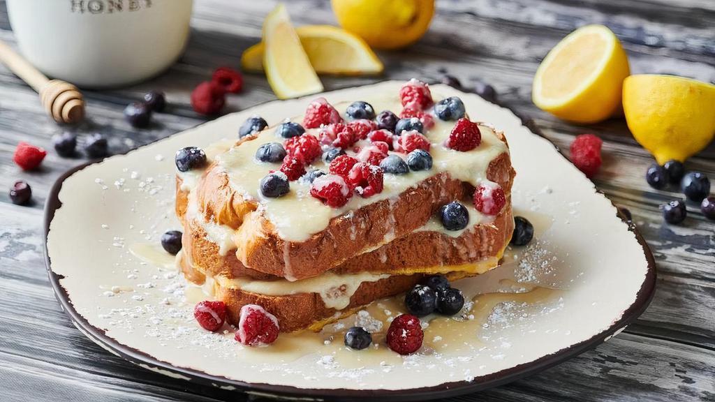 Honey Lemon Ricotta French Toast · Three slices of Challah bread dipped in French toast batter and griddled to perfection. Topped with with sweet honey lemon ricotta, fresh raspberries and blueberries, lemon icing, and powdered sugar.