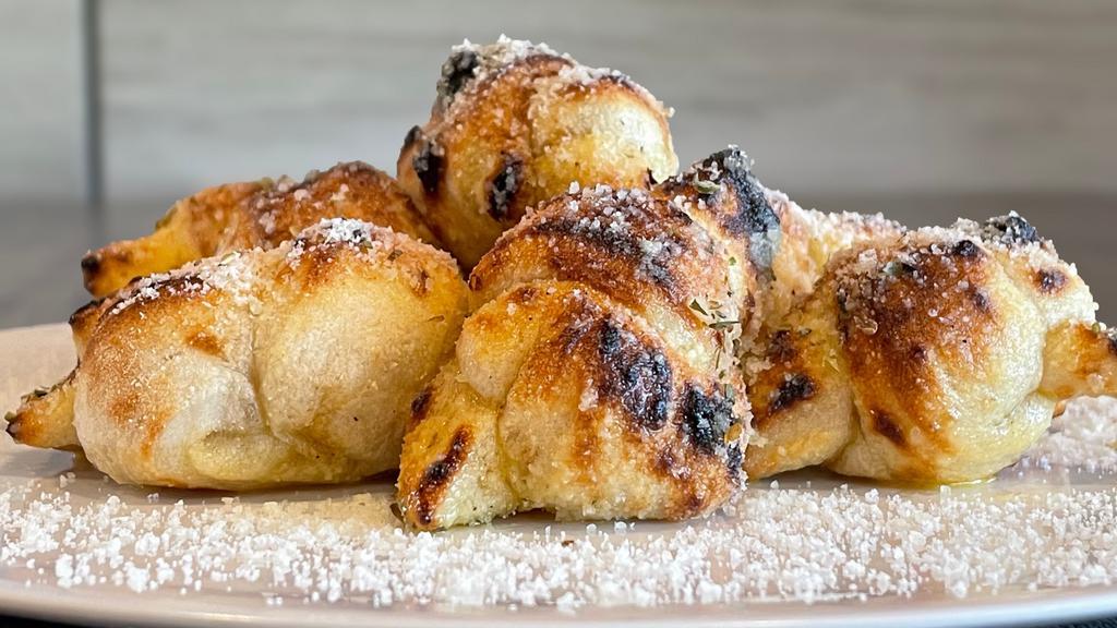 Garlic Knots · fresh dough baked into 8 knots and covered in garlic butter, parmesan cheese and oregano and served with a side of our signature pizza sauce.
