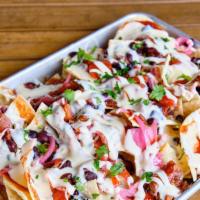 Chopped Brisket Nachos · Smoaked brisket with queso, pickled jalapeños, red onions, black beans, cilantro, and your c...