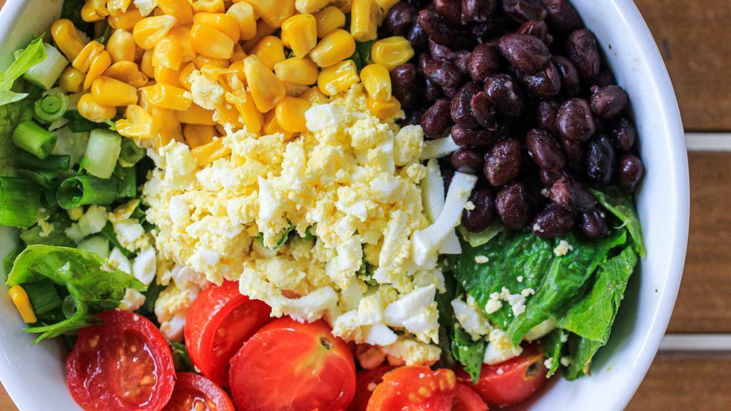 Q Chopped Salad · Chopped romaine lettuce, grilled corn, green onion, black beans, a chopped egg, and cherry tomatoes. We recommend the cilantro-lime dressing.