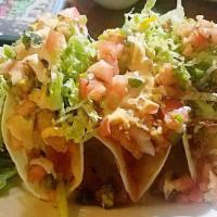 Fish Tacos · Three crispy fish tacos topped with chipotle sauce and pico de gallo.