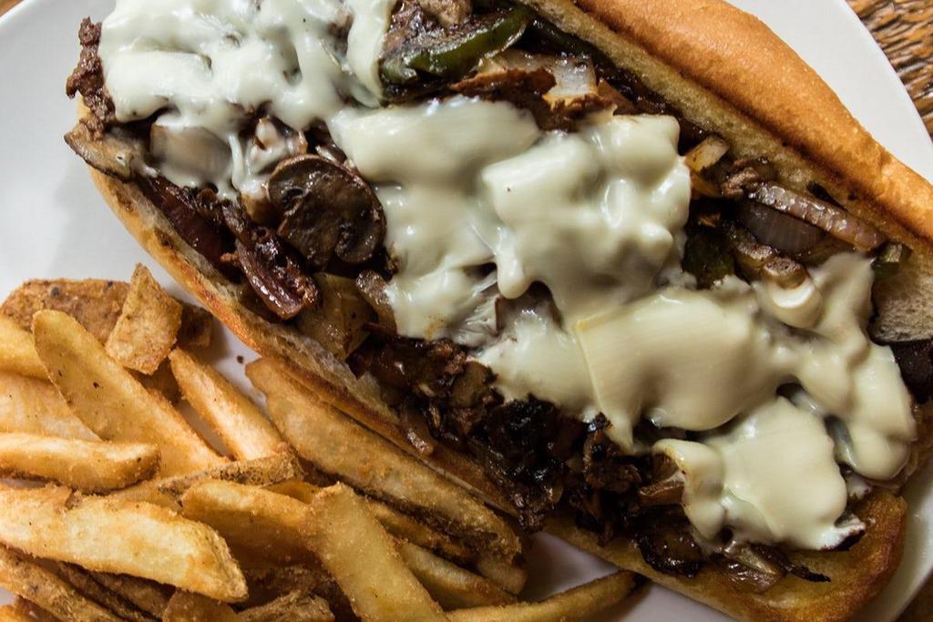 Classic Philly Cheesesteak · Thinly sliced brisket & sirloin, caramelized onions, grilled mushrooms & green peppers, aged provolone, hoagie roll.