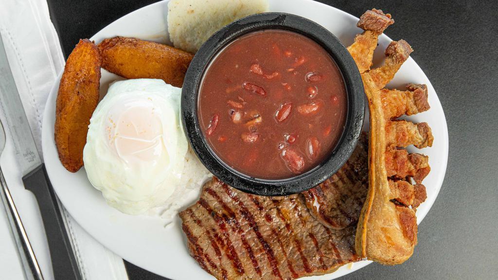 Bandeja Paisa · Bistec a la parrilla o carne molida, plátanos dulces, frijoles, panza de cerdo, arepa y arroz cubierto con un huevo frito. / Grilled steak or ground beef, sweet plantains, beans, pork belly, arepa and rice topped with a fried egg.