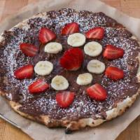 Nutella Pizza · Sweet pizza dough slathered with Nutella, fresh strawberries and bananas, and powdered sugar.