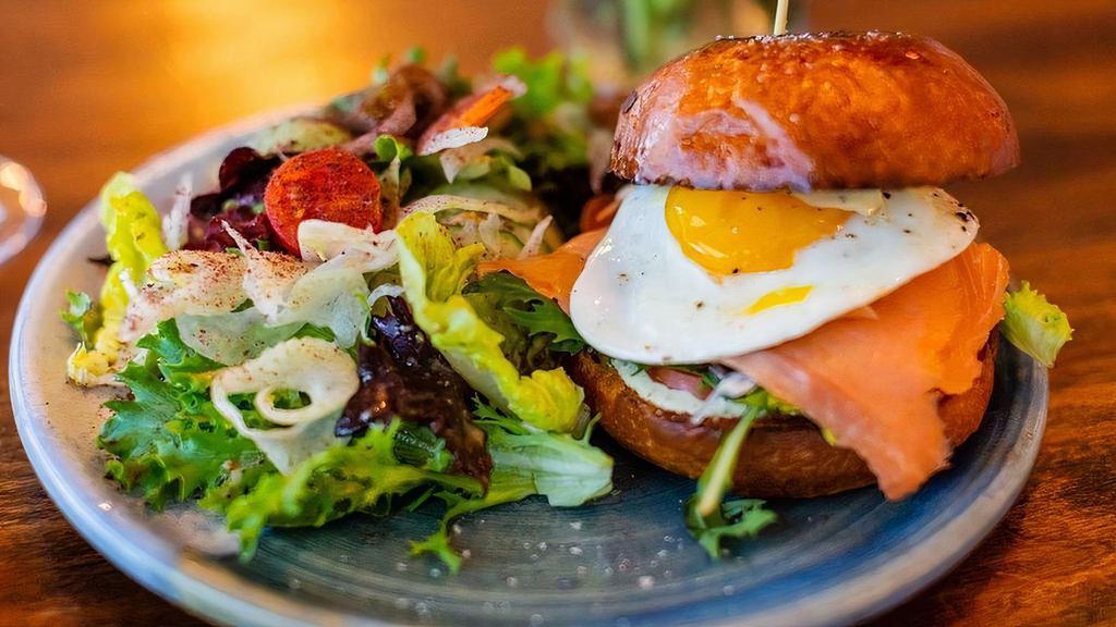 Smoked Salmon Sandwich · nordic smoked salmon(sushi style), lettuce, tomato, red onions, dijonaise, capers, sunny-side up egg, brioche bun with a petit salad