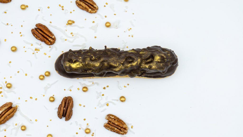 German Chocolate Eclair · The rich flavor of the German chocolate cake inspired us to make a new flavor in our eclair collection! Chocolate cream filling topped with a rich sticky coconut and pecan paste dipped in hard dark chocolate with touches of gold.