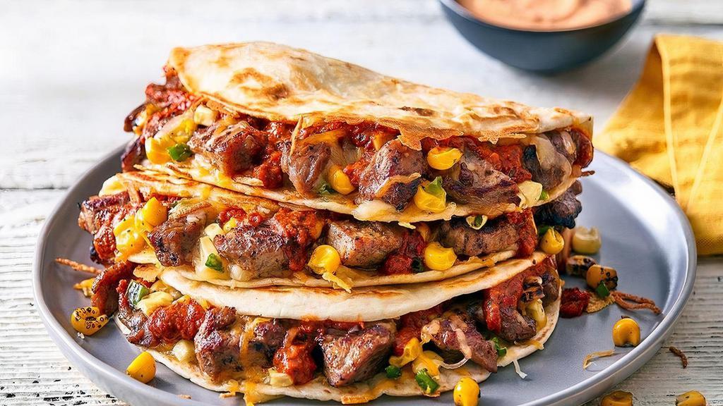 Steak Fajita Quesadillas · Fajitas done Papa’s way. Marinated grilled steak, fire-roasted corn, melted blended cheese and a red pepper sauce. Served in 3 grilled flour tortillas with red pepper ranch dressing.  Served with a side of Papa’s Tortilla Chips