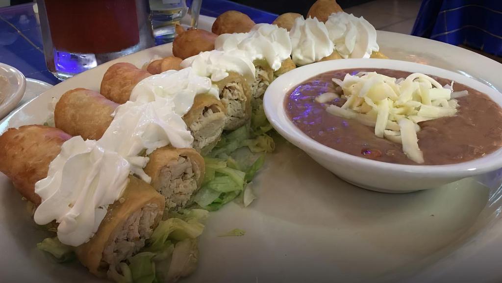 Flautas · 8 crispy chicken tacos with green tomatillo sauce, refried beans, and sour cream.