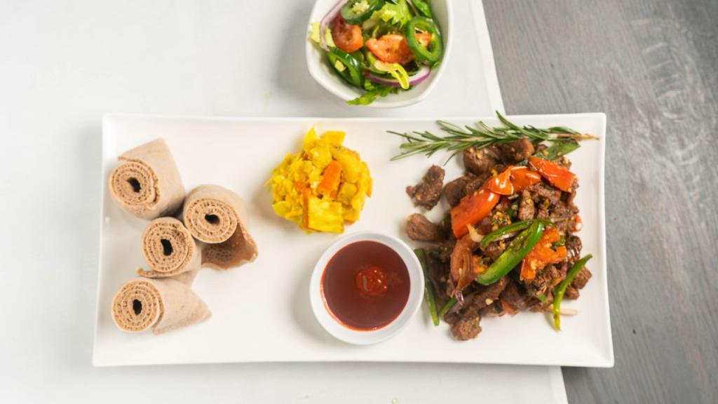 Lamb Tibs · Marinated Juicy and Tender cubed Lamb meat  sautéed with red onions, fresh tomatoes, garlic, ginger,  jalapeno papers, rosemary and spiced butter.
The Tibs comes  with one Veggie side item