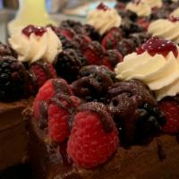 Chocolate Cheesecake Bar · A chocolate cheesecake bar with an Oreo crust, topped with raspberry puree, strawberries, bl...