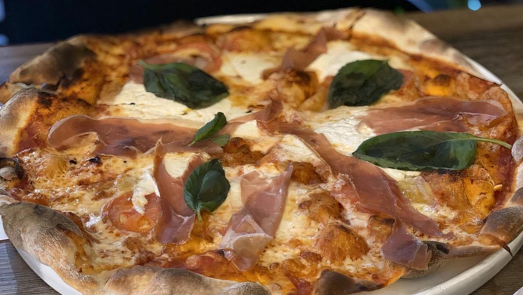 Pizza Montecatini · Salsa de tomare, mozzarella fresca, burrara, prosciutto, tomate natural, ajo laminado y albahaca fresca.