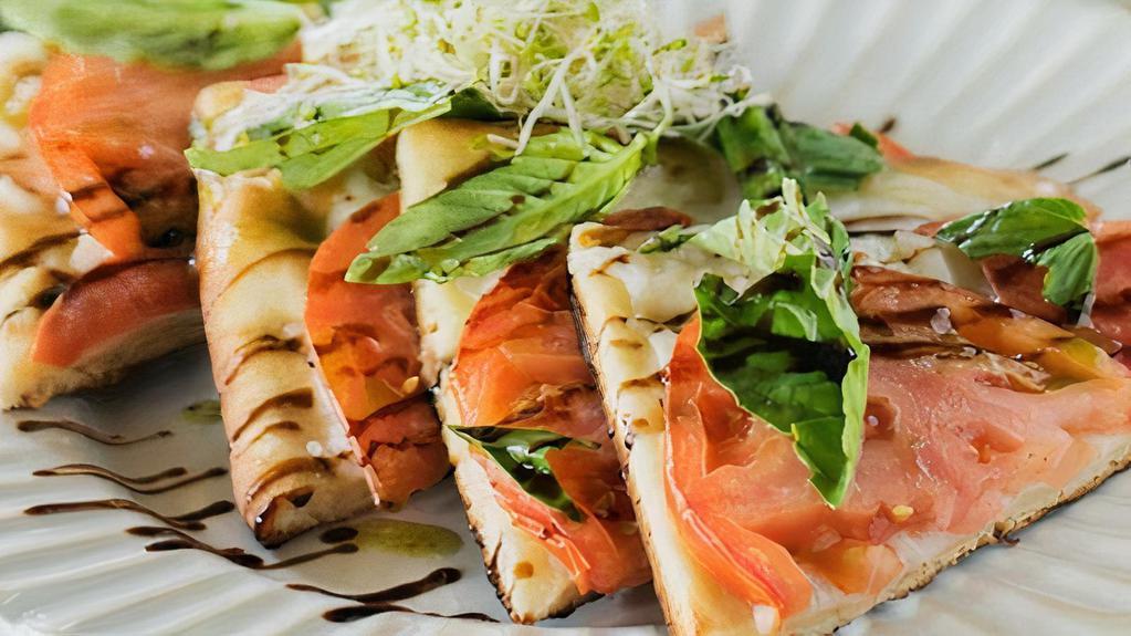 Caprese Pizzeta · Vegan mozzarella, tomato, fresh basil topped basil oil, balsamic glaze and sprouts