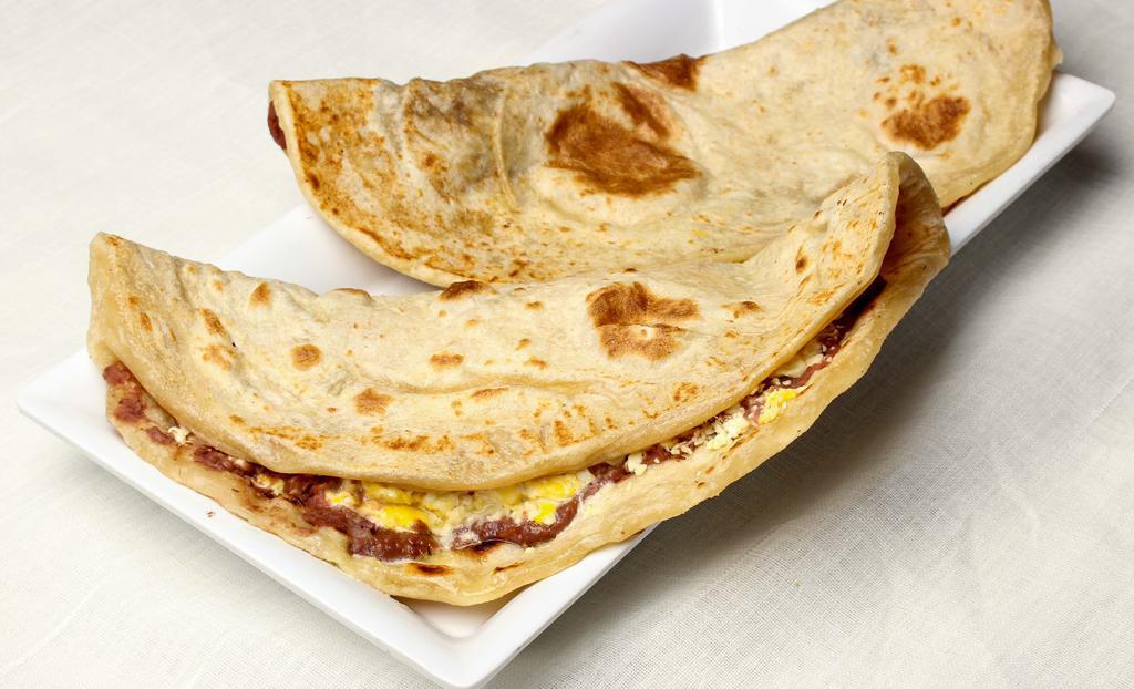 Baleada Sencilla · Flour tortilla, folded in half-filled with mashed fried beans, cheese, and cream.