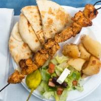 Chicken Kebab Platter · Two skewers of chicken breast chunks with lemon potatoes, Greek salad, and pita bread.