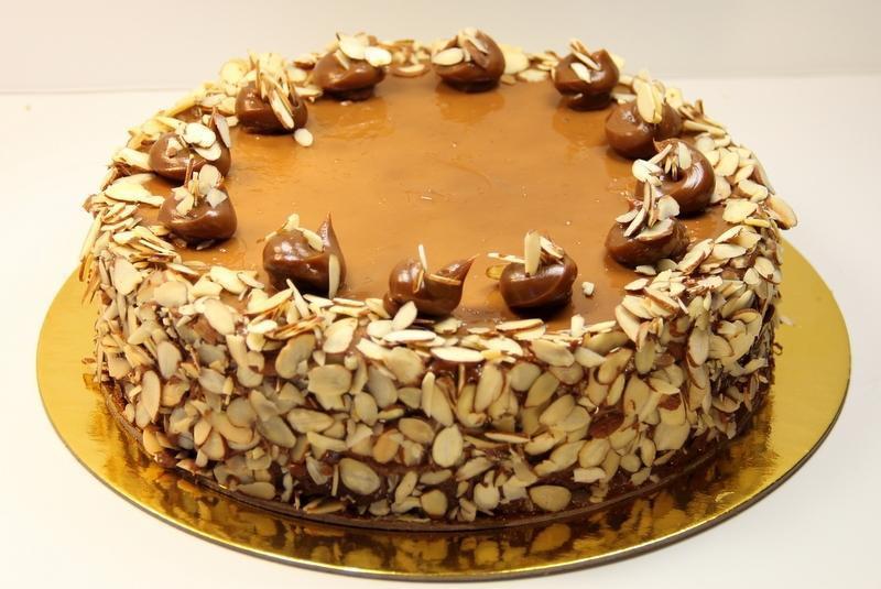 Dulce De Leche Rum Cake · Vanilla rum cake filled and iced with dulce de leche topped with toasted sliced almonds.