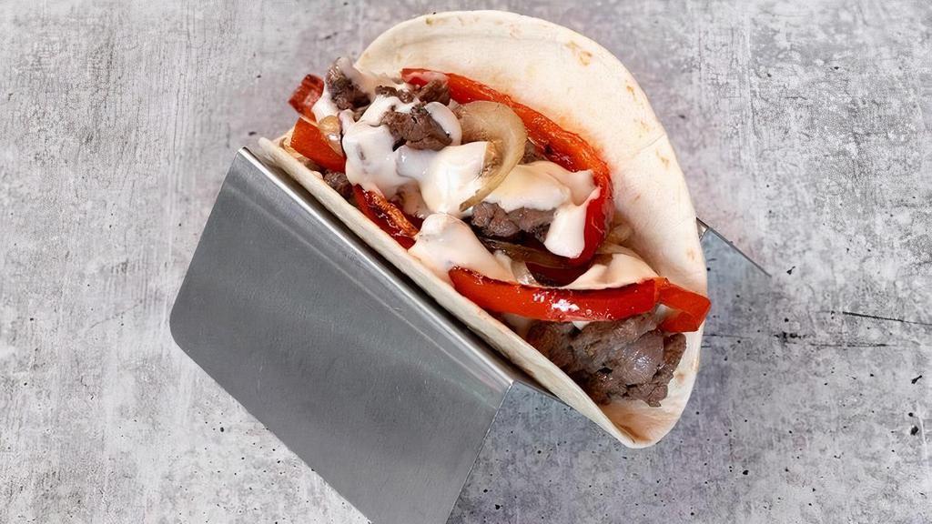 Steak & Cheese Philly Taco · grilled steak, queso blanco, grilled peppers and onions