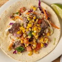 Steak And Street Corn Taco · Grilled sirloin steak with house slaw, roasted corn salsa, and cotija cheese on a flour tort...