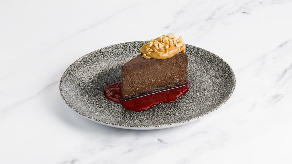 Peanut Butter + Chocolate Cheesecake · Peanut butter mousse, raspberry coulis, crushed peanuts.