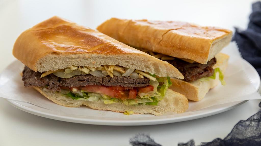 Pan Con Bistec (Steak Sandwich) · Palomilla steak with sauteed onions, lettuce, tomatoes and potato stixs on a soft cuban bread.