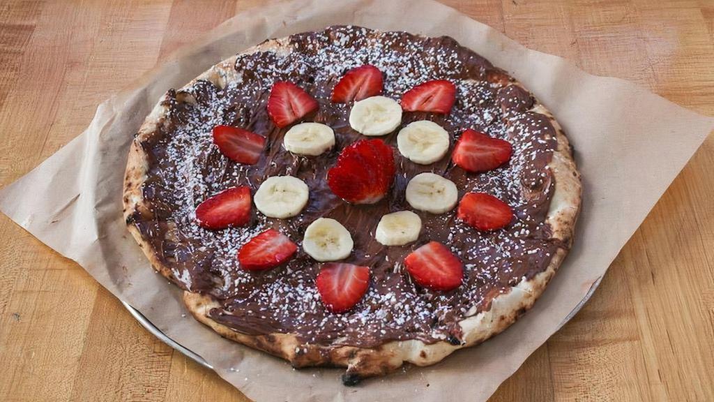 Nutella Pizza · Sweet pizza dough slathered with Nutella, fresh strawberries and bananas, and powdered sugar.