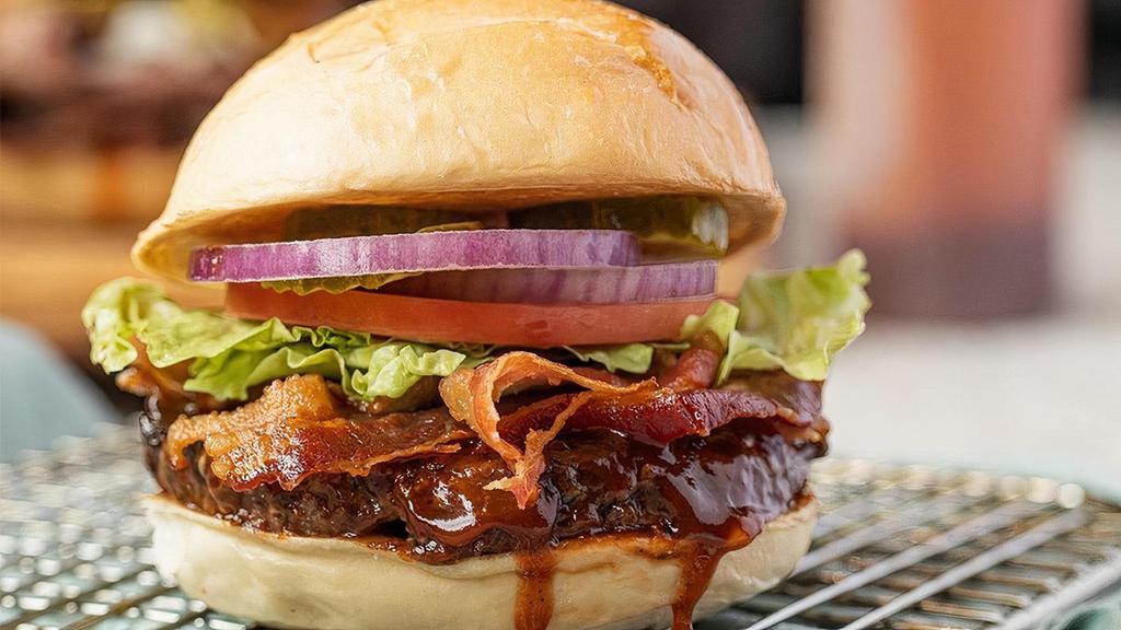 Bbq Bacon Burger · Flamed grilled burger brushed with tangy BBQ sauce, topped with bacon lettuce, tomato, onion and pickle on a toasted bun.