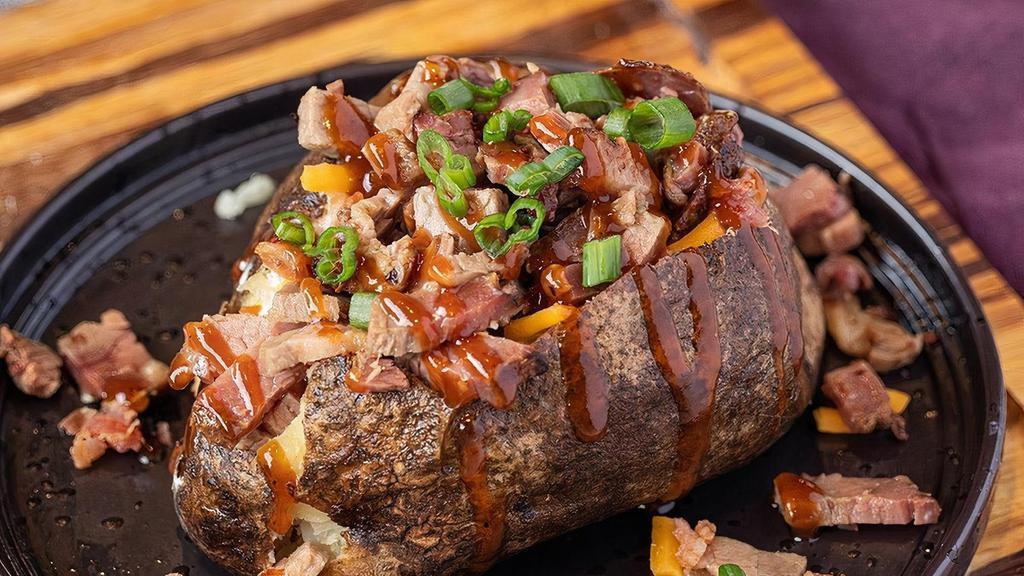Brisket Spud · Packed with low and slow-cooked prime brisket, covered with BBQ sauce and topped with bacon pieces, sour cream, cheddar cheese, and butter