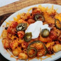 Chili Cheese Tots · Mound of tater tots smothered with chili, jalapeños, shredded cheddar, and sour cream.