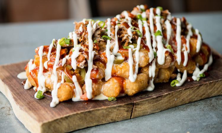 Pork Totcho · tater tot mountain with bbq pulled pork, pico de gallo, jalapenos, cheddar cheese, white queso, sour cream, bbq sauce