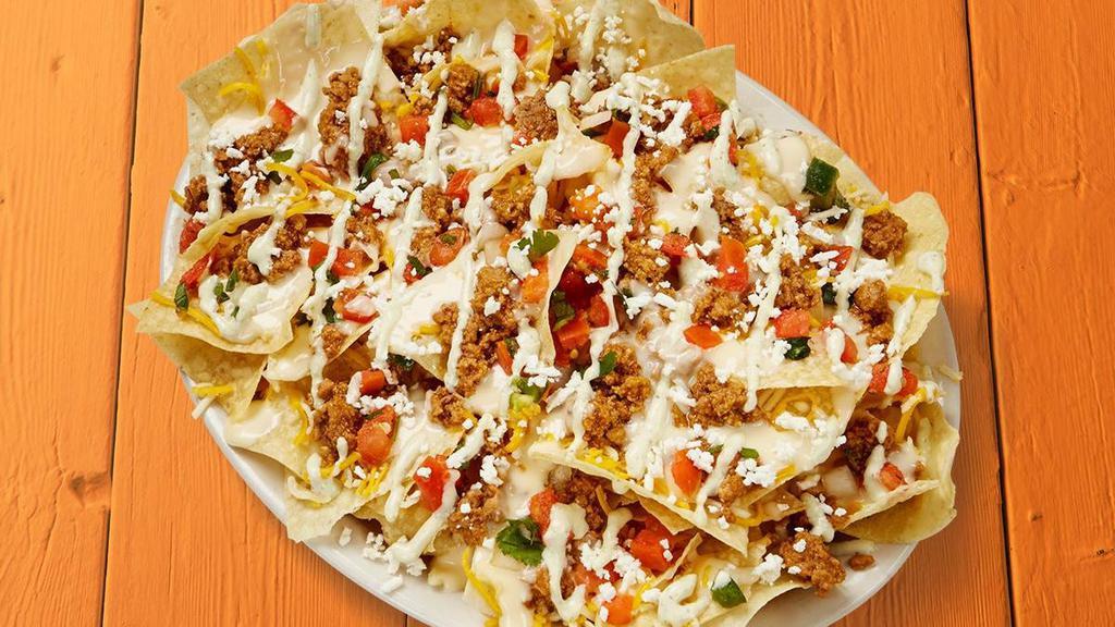 Seasoned Ground Beef Nachos · Fresh tortilla chips topped with special ground beef, shredded cheese, queso, feta, pico de gallo, and garlic sauce.. {DF - remove queso, shredded and feta cheese}