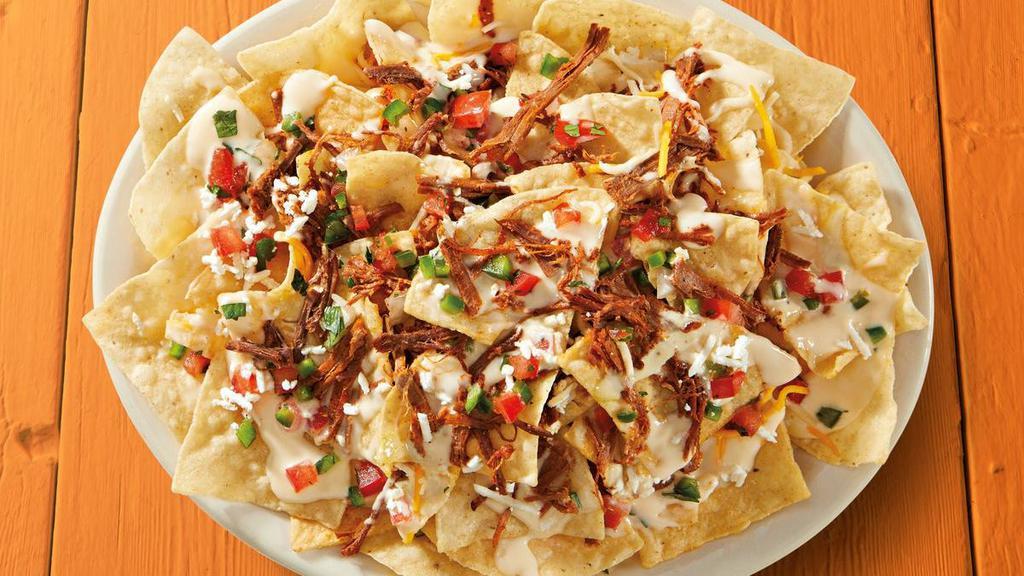 Shredded Brisket Nachos · Fresh tortilla chips topped with shredded brisket, shredded cheese, queso, feta, pico de gallo, and garlic sauce.. {GF} = Gluten Friendly *please note that chips are fried in a fryer that may allow cross contact in some locations. {DF - remove queso, shredded and feta cheese}