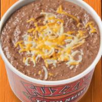 Refried Beans · Refried beans topped with shredded cheese.. {GF}, {DF - remove shredded cheese}