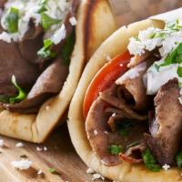 Lamb Gyro Combo · Sliced lamb set on pita bread topped with lettuce, tomatoes, onions, and tzatziki sauce serv...