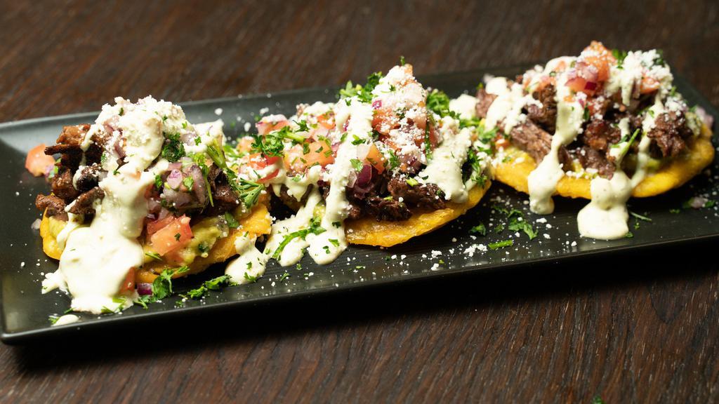 Loaded Tostones · 3 Tostones topped with churrasco, guacamole, pico de gallo and cilantro aioli