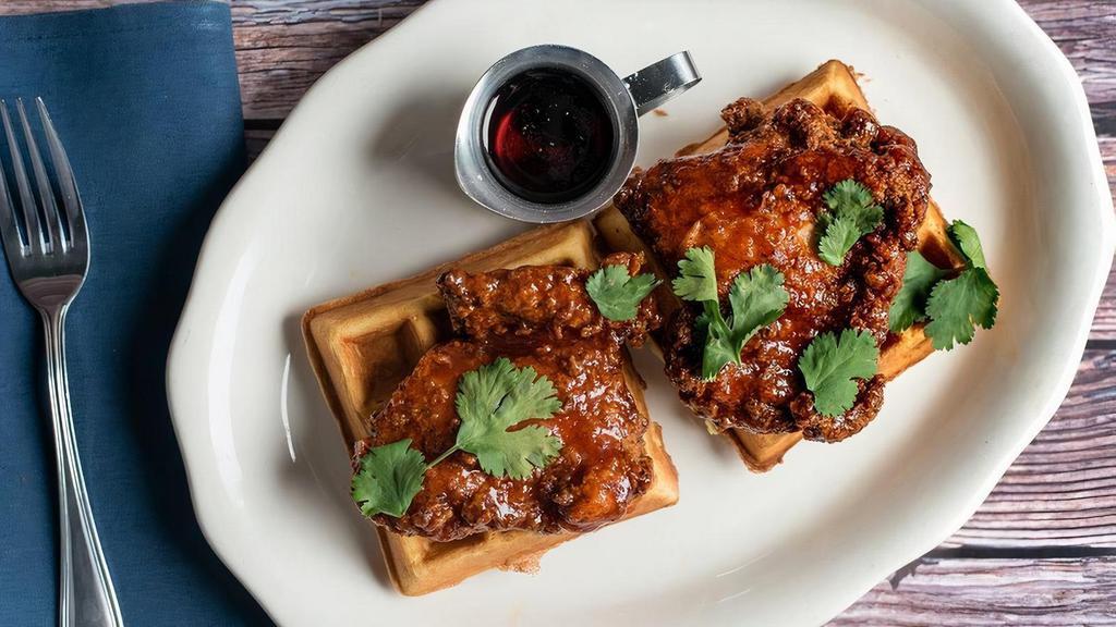 Sriracha Honey Fried Chicken* & Waffles · the perfect sweet, spicy & savory fried chicken with cilantro,. over fluffy buttermilk waffles