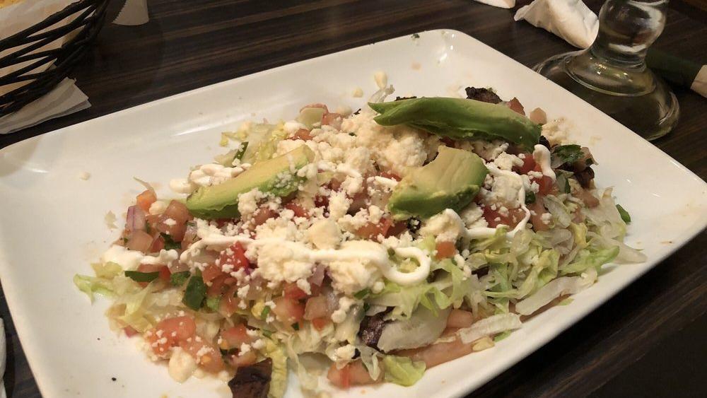 Authentic Mexican Huarache · Choice of steak, chicken, or shrimp on an original, freshly made long thick corn tortilla topped with Mexi-beans, lettuce, pico de gallo, queso fresco, crema, and slices of fresh avocado.