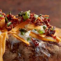 Not-So-Naked Potato · A large baked potato topped with bacon, cheddar cheese, butter, sour cream, and scallions.