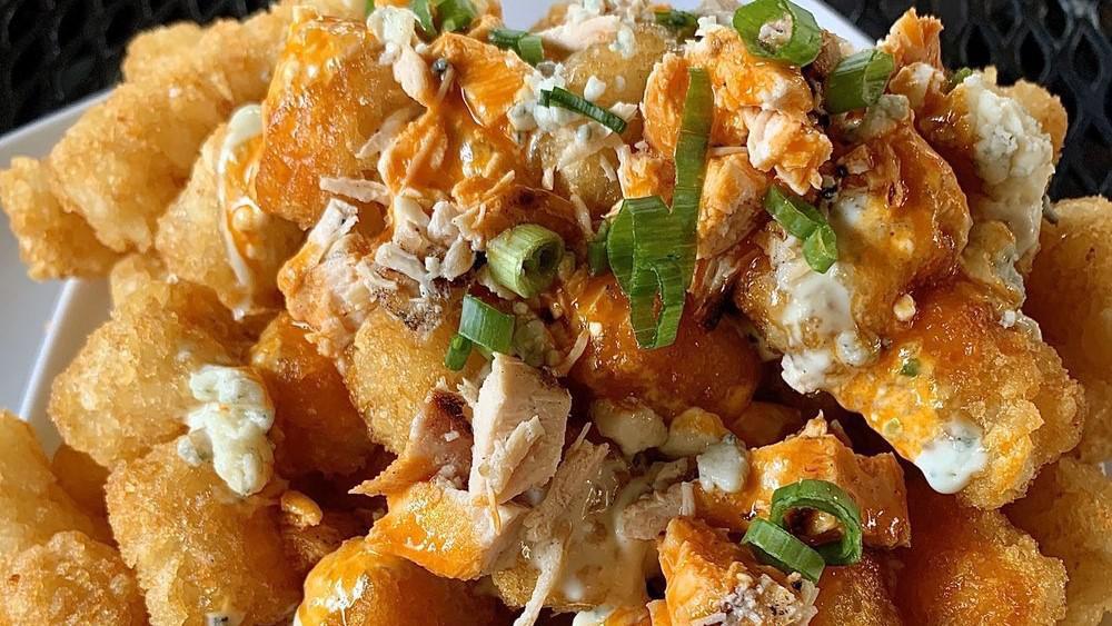 Buffalo Chicken Totchos · Tots smothered with grilled chicken in our spicy buffalo sauce, blue cheese dressing and topped with green onions and blue cheese crumbles.