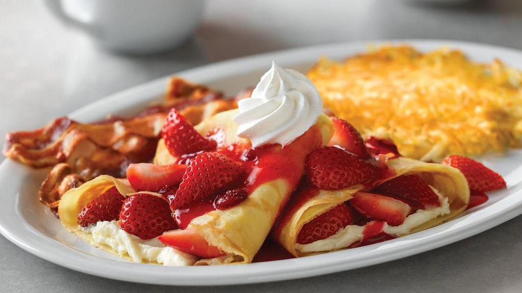 Strawberry Crêpes Combo · Two strawberries and cream crêpes, served with hash browns and two bacon strips or two sausage links.