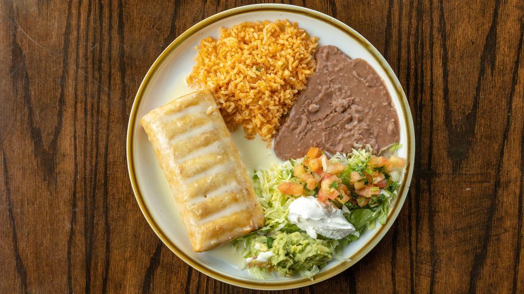 Agave Chimichanga · Your choice of ground beef or shredded chicken. Topped with queso and served with rice beans and guacamole.
