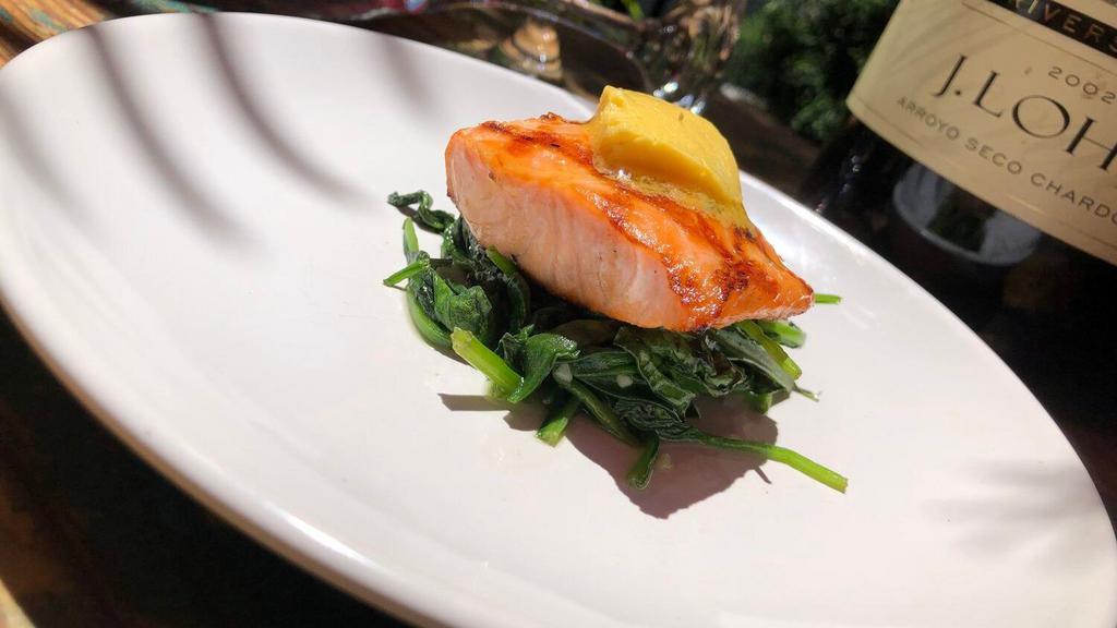 Salmón Al Sarten · Roasted salmon over sautéed spinach with herbed butter.