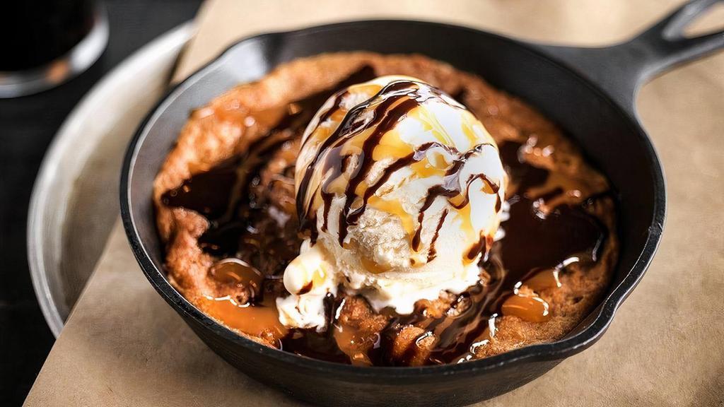 Salted Caramel Cookie Skillet · Fresh out of the oven salted caramel almond cookie, topped with vanilla bean ice cream and drizzled with caramel & chocolate sauce.