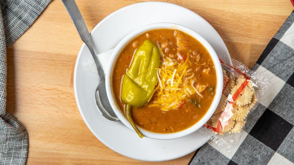 White Chicken Chili · South western style chlii with grilled white meat chicken, white navy beans, green and red bell pepper, celery, green chiles, garlic and onion, garnished with shredded monterey jack and cheddar cheese.