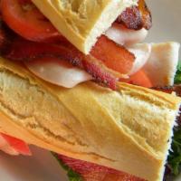 Turkey Club Sandwich · sliced smoked turkey, peppered maple bacon, arugula, tomatoes & mayo on a French baguette se...