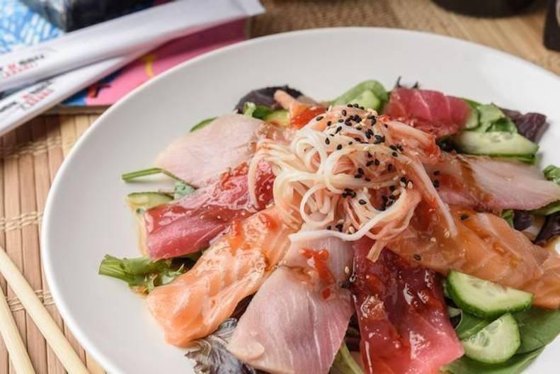 Spicy Sashimi Salad · Three sashimi rockstars—red tuna, salmon, yellowtail—crab stick and cucumber piled on spring mix with sweet chili, ponzu, sriracha, eel sauce and sesame seeds.