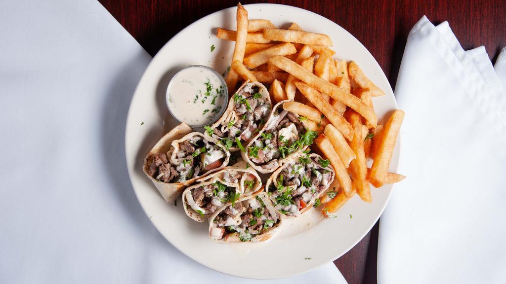 Arabic Beef Shawarma · Slices of marinated beef broiled with tomatoes, pickles, onions, fresh parsley, somaq, and tahini sauce.